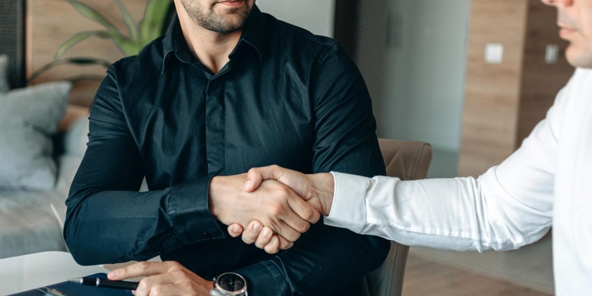 Two business partners shaking hands, symbolizing a successful agreement and established trust in the real estate market.